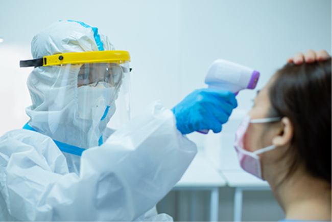 רופאה ממוגנת מודדת חום לאישה כדי לבחון אפשרות להתפתחות של מחלה זיהומית מדבקת